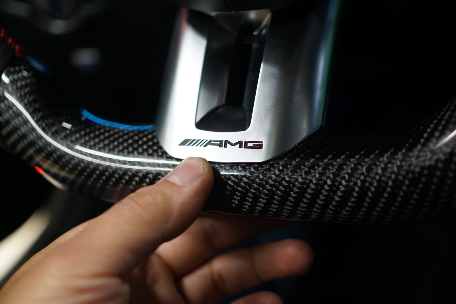 벤츠 W213 E클래스 익스클루시브 (18년식) 핸들 하단 AMG 엠블럼과 카본 마감 디테일입니다.